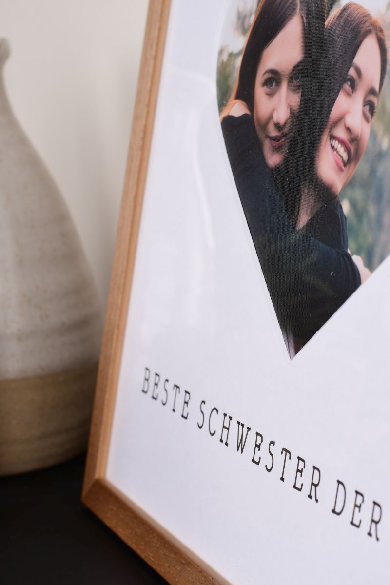 Primer plano de un marco de fotos de 30x30 en roble con recorte de corazón para la mejor hermana del mundo